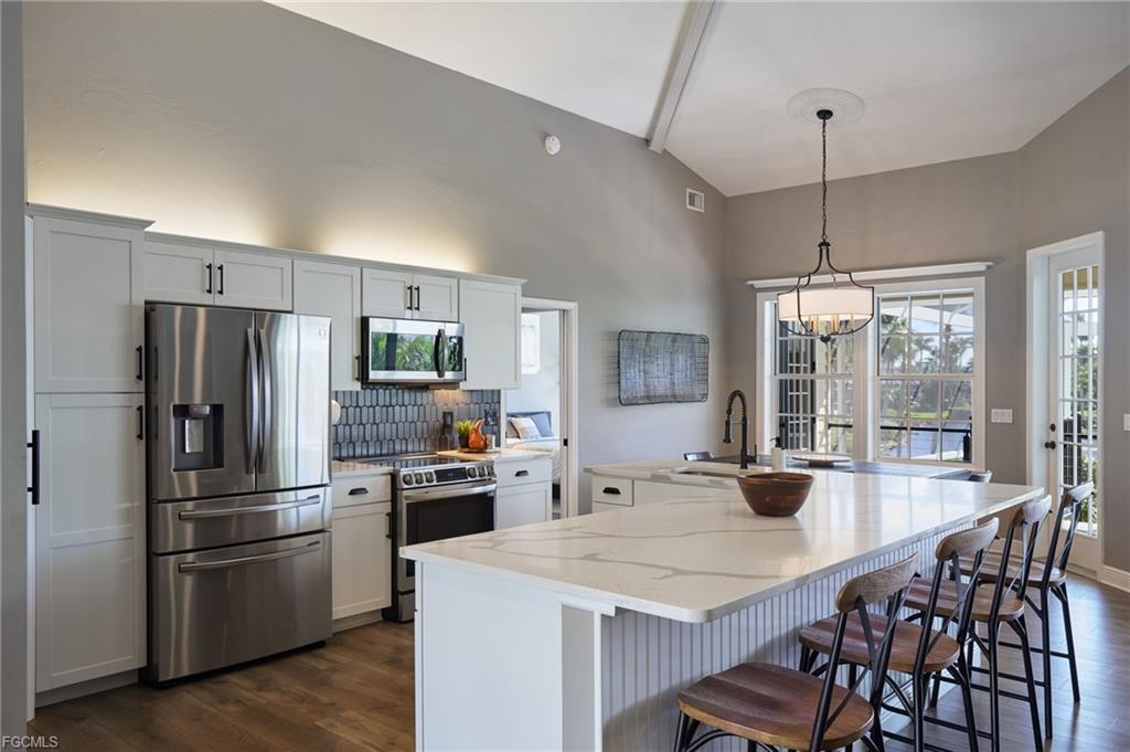 Kitchen with stainless appliances under vaulted beamed ceilings
